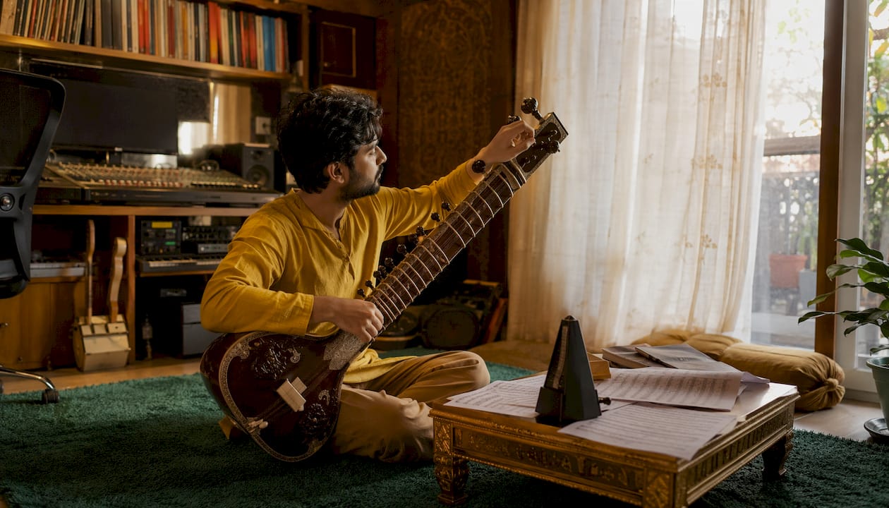 Composer tuning sitar in home studio
