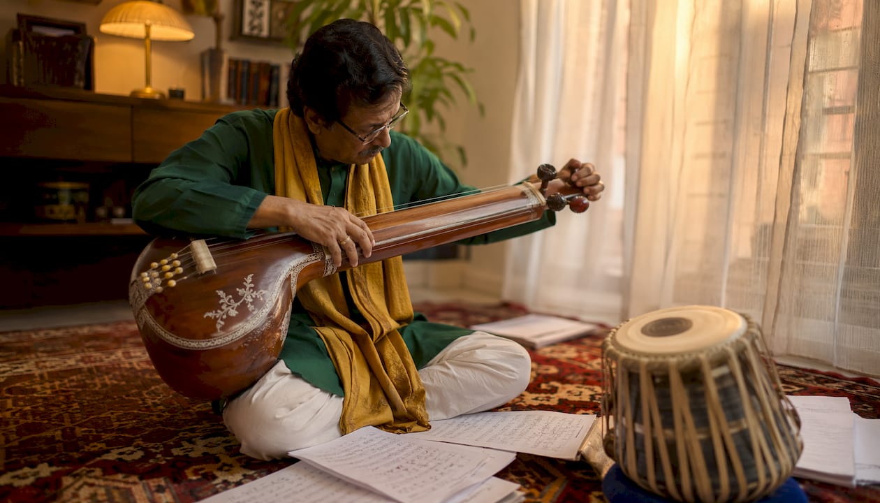 Indian classical singer tuning tanpura during practice