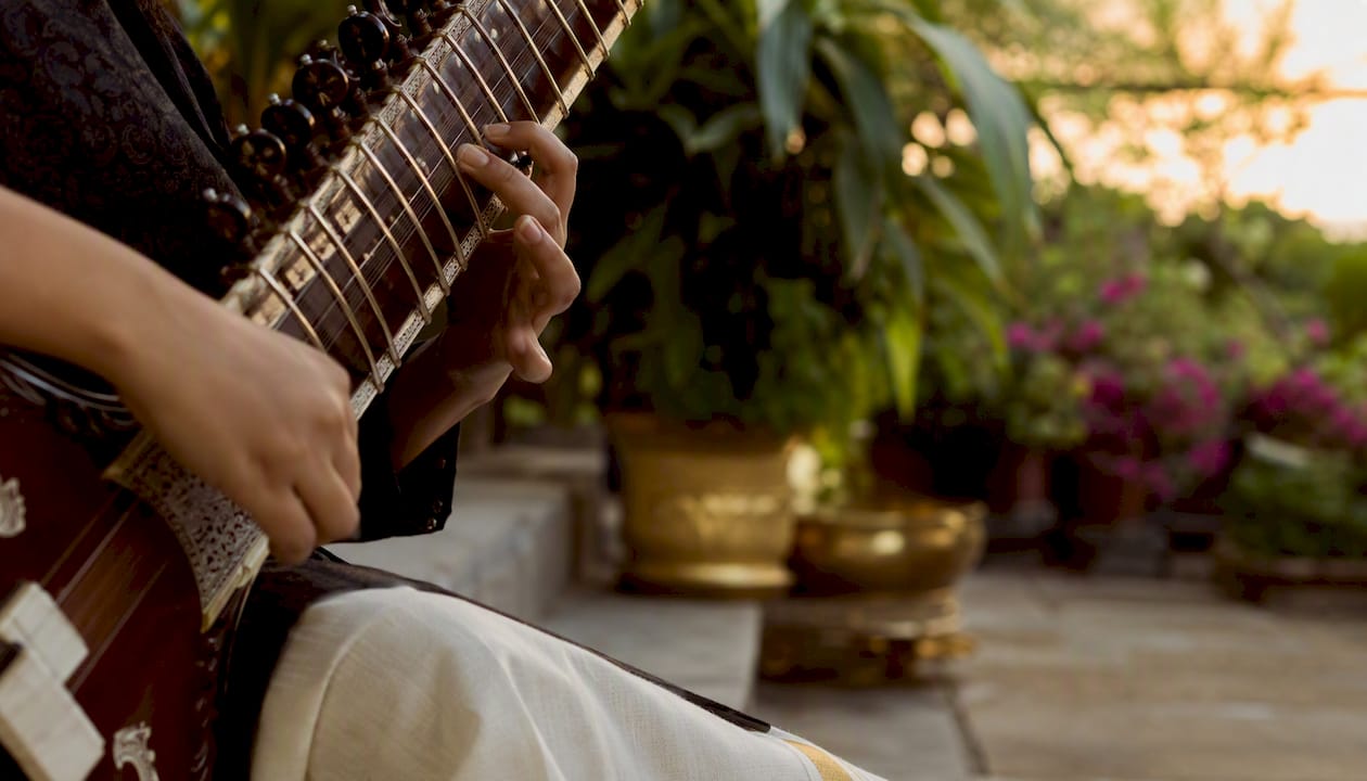 Hands playing sitar in warm practice room