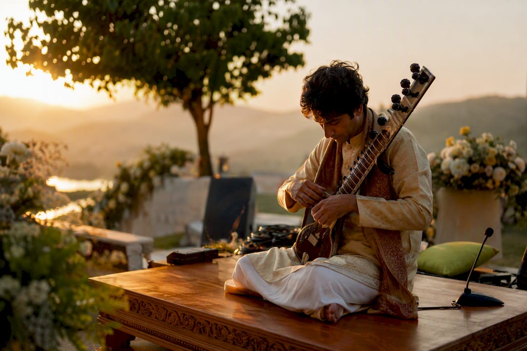 Rajib Karmakar sitarrajib What Is a Destination Wedding Music Act? A Planning Guide 1 Sitarist tuning sitar outdoors at wedding