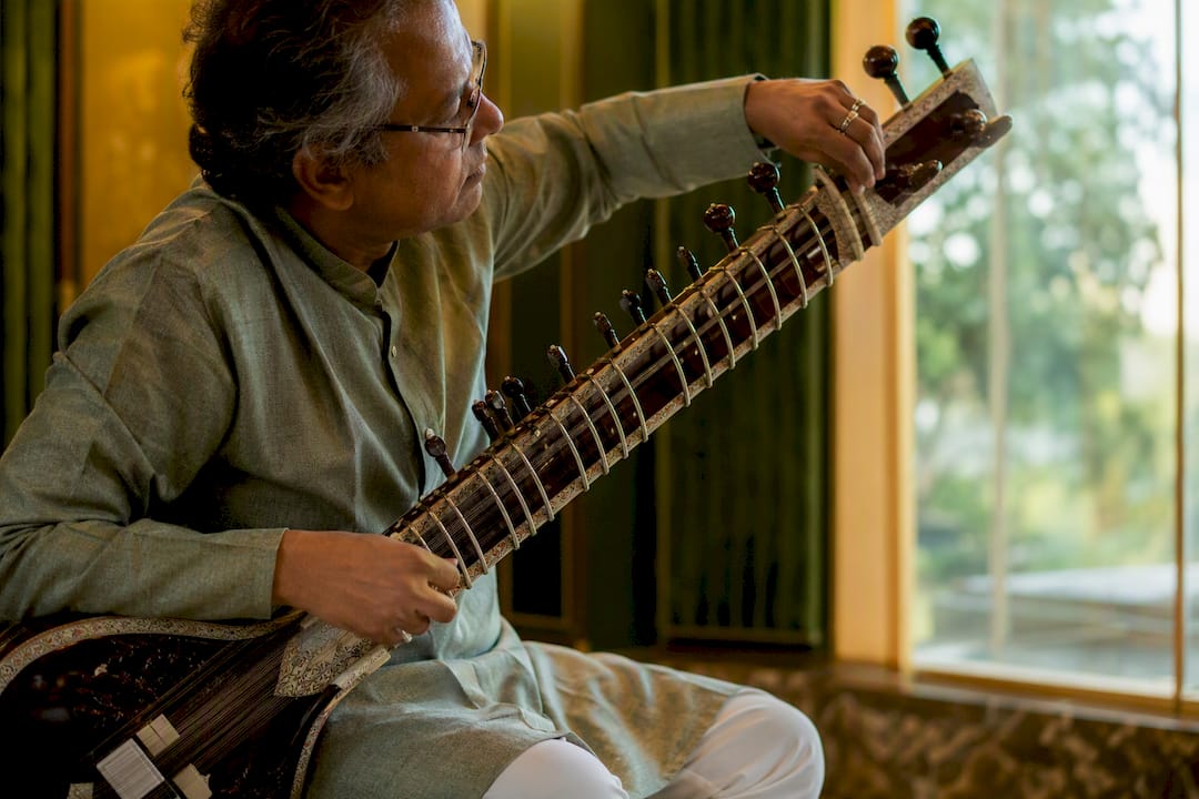 Rajib Karmakar sitarrajib How to Book Corporate Event Music: A Sitar Hiring Guide 1 Sitar musician tuning instrument on event stage