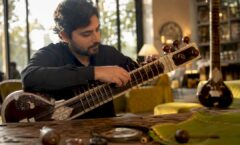 Musician tuning sitar in warm studio